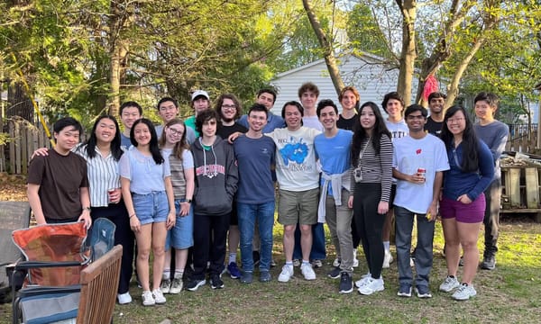 Group photo of the 2024 UPL'ers posing together in a backyard with trees and a house in the background.